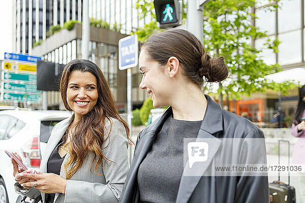 Geschäftsfrauen lächelnd beim Verlassen des Hauses nach der Arbeit in der Stadt