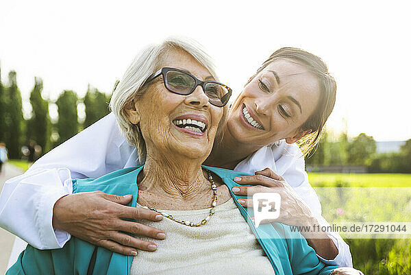 Happy senior woman with female caretaker in park