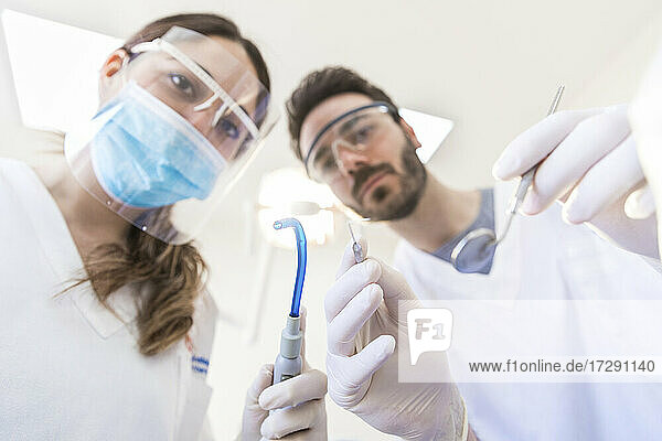 Zahnärztin mit Mitarbeiterin  die zahnärztliche Geräte in der Klinik hält