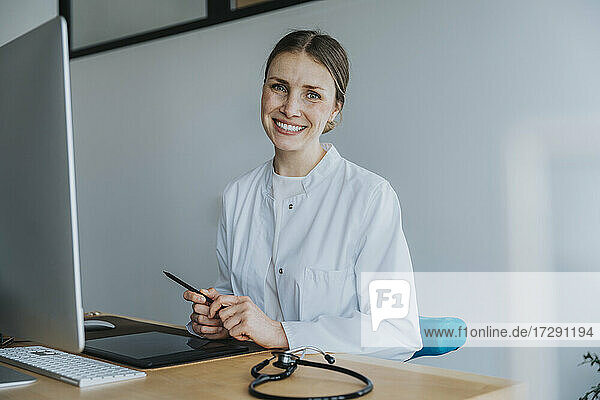 Lächelnder Arzt am Schreibtisch sitzend