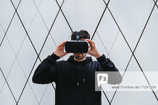 Mann hält Virtual-Reality-Headset an der Wand