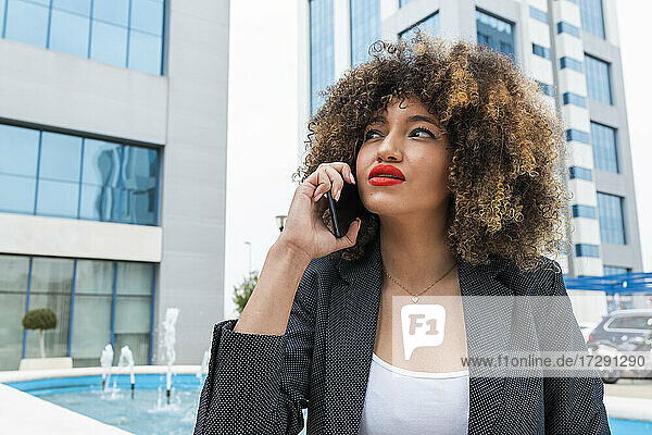 Beautiful Afro female professional talking on mobile phone in city