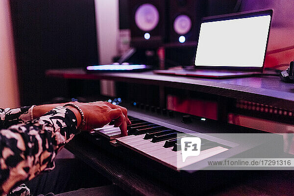 Junger männlicher Komponist spielt Klavier vor einem Laptop im Studio