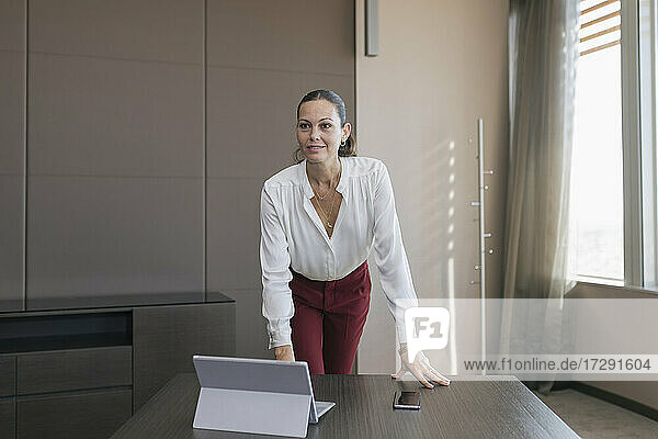 Weibliche Fachkraft mit Laptop und Mobiltelefon am Schreibtisch im Büro stehend