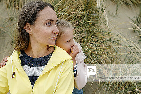 Mother and daughter looking away while spending leisure time at beach