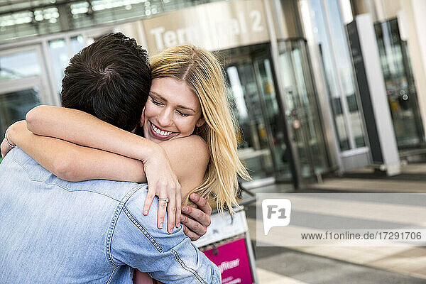 Junges Paar  das sich vor dem Flughafen umarmt