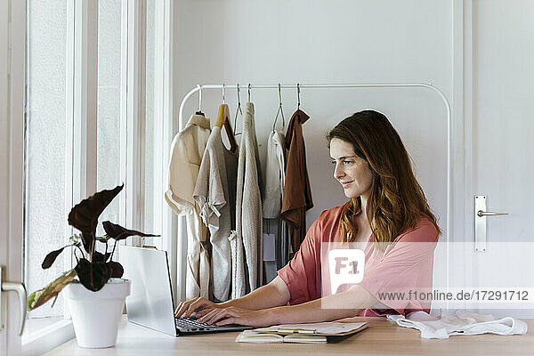 Modedesignerin mit Laptop bei der Arbeit zu Hause