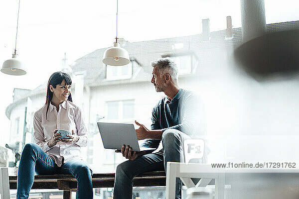 Männliche und weibliche Unternehmer im Gespräch in einem Café