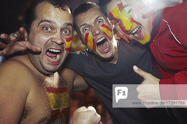 Männlicher Sportfan mit spanischer Flaggenfarbe im Gesicht