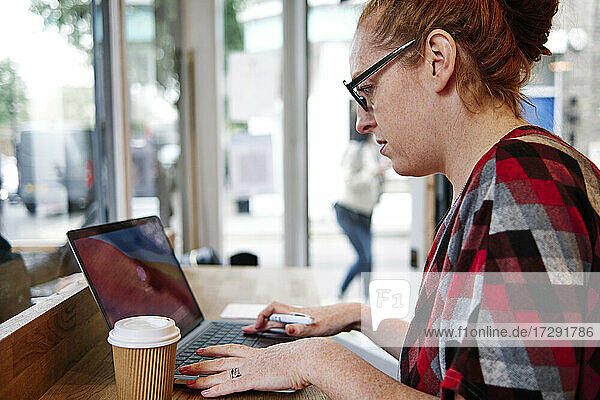 Frau mit Brille benutzt Laptop in einem Cafe