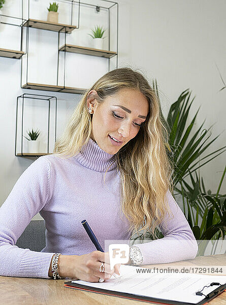 Female professional with blond hair signing documents in office