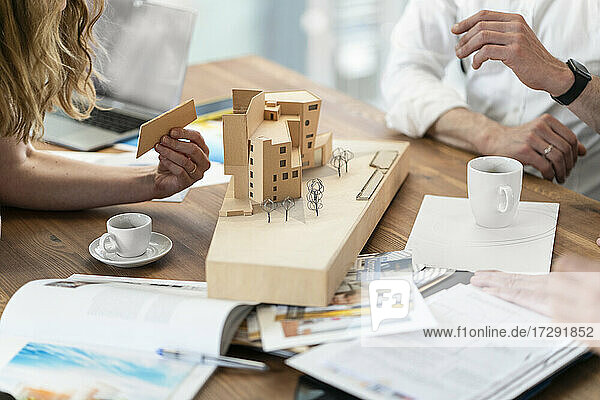 Architektin arrangiert Architekturmodell mit männlichen Kollegen am Schreibtisch im Büro