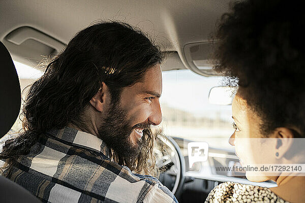 Girlfriend looking at smiling boyfriend in car
