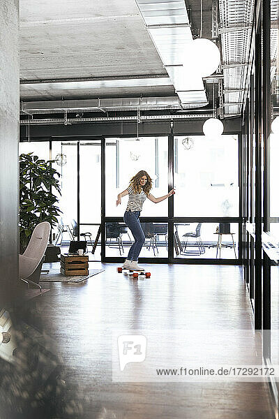 Businesswoman riding skateboard in office