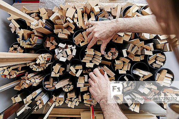 Männlicher Rahmenbauer  der bei der Arbeit Holzbretter aus einem Regal auswählt