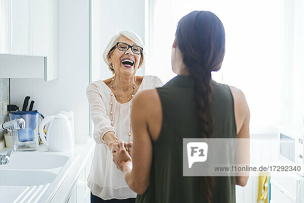 Fröhliche ältere Frau im Gespräch mit ihrer Enkelin in der Küche zu Hause