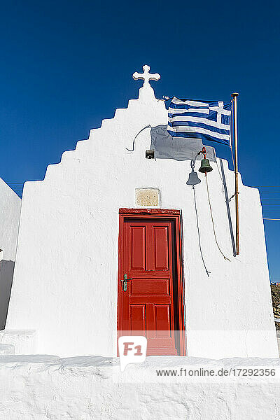 Weiß getünchte Kirche mit griechischer Flagge in Mykonos  Griechenland