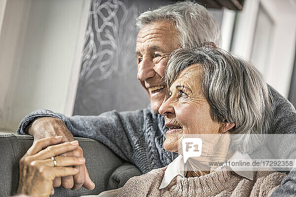 Ältere Frau hält die Hand ihres Mannes im Wohnzimmer
