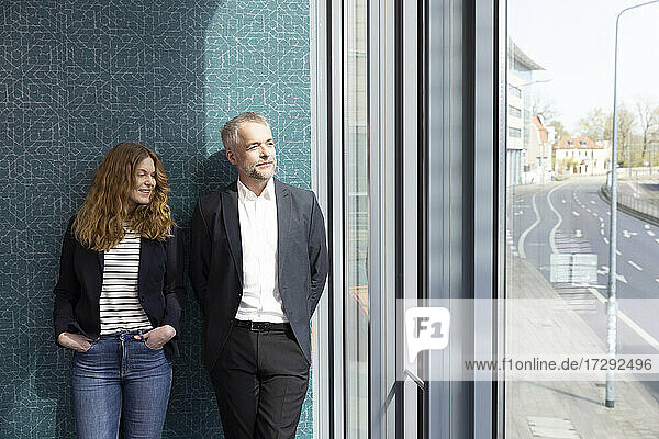Male and female entrepreneur standing in front of wall at office