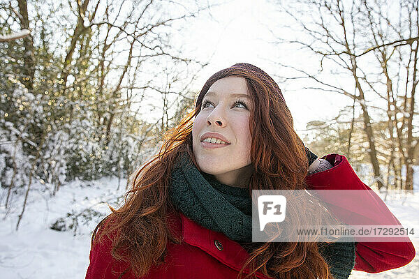 Rothaarige Frau schaut nach oben und genießt den Winter