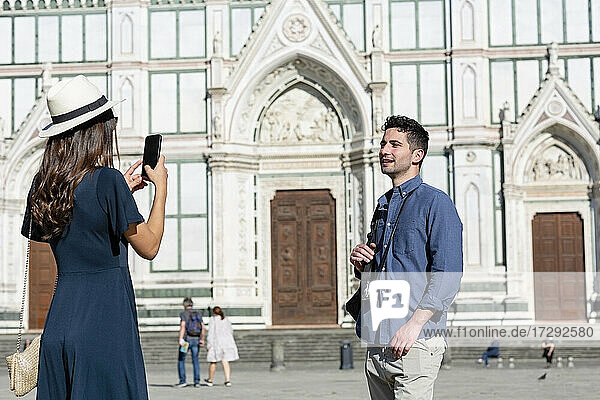Weiblicher Tourist fotografiert Mann durch Smartphone auf der Piazza Di Santa Croce  Florenz  Italien