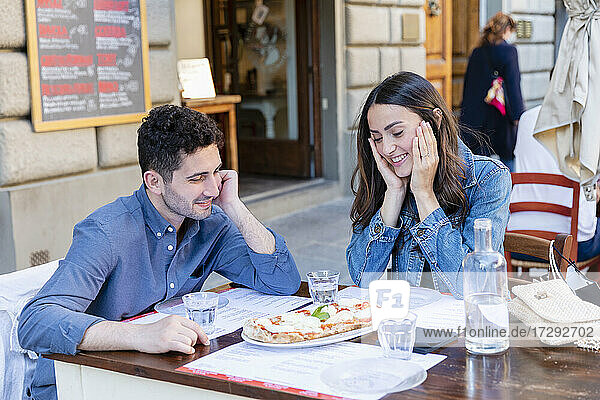 Paar lächelt bei der Betrachtung einer Pizza auf dem Tisch