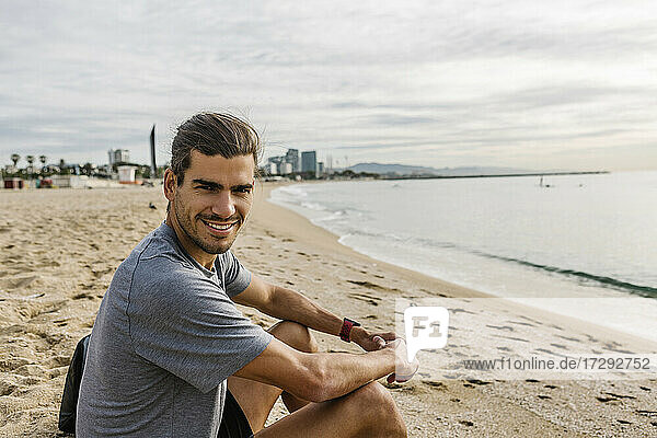 Sportsman smiling while sitting on beach