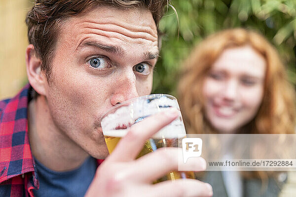 Mann mit hochgezogenen Augenbrauen trinkt Bier in einer Kneipe