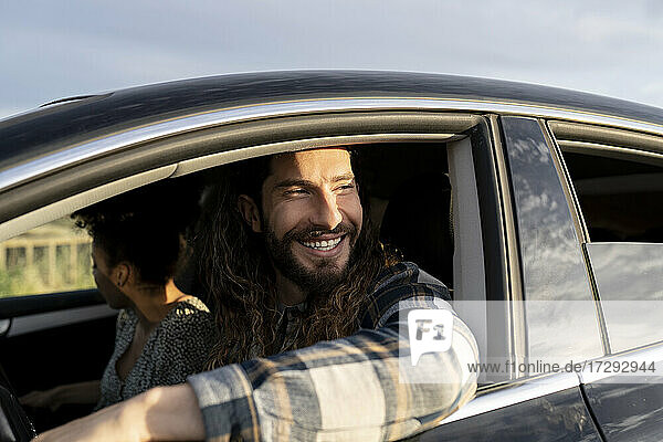 Mid adult man smiling while looking way in car