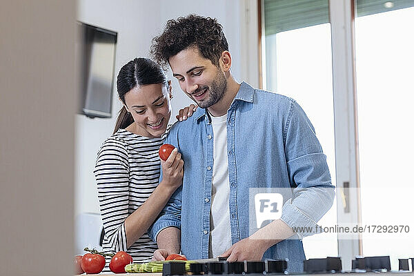 Lächelndes Paar  das gemeinsam in der Küche zu Hause Lebensmittel zerkleinert