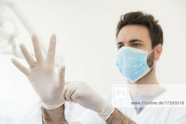 Männlicher Zahnarzt mit Schutzhandschuhen in einer medizinischen Klinik