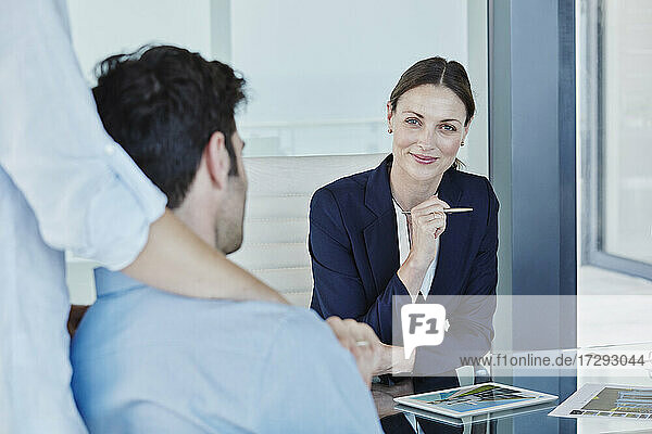 Lächelnde Geschäftsfrau im Gespräch mit einem männlichen und einem weiblichen Kunden