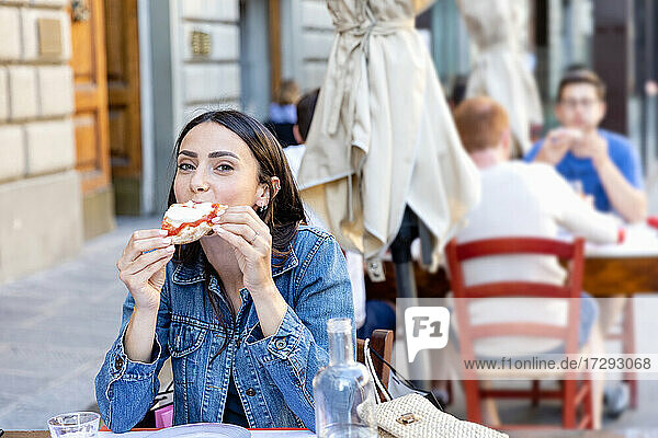 Weiblicher Tourist isst Pizza in einem Straßencafé