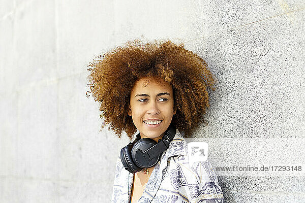 Junge Afro-Frau mit Kopfhörern vor einer Wand