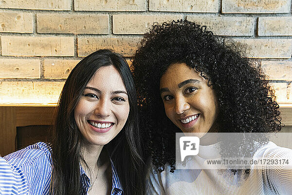 Smiling female friends taking selfie at bar