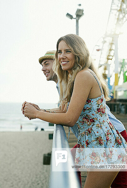 Lächelndes Paar lehnt am Geländer des Santa Monica Pier