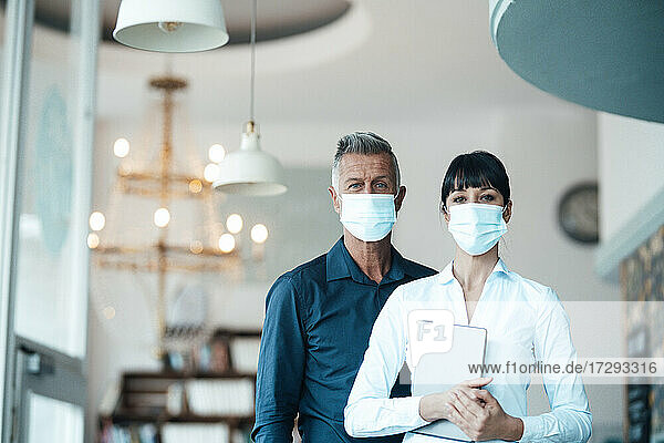 Männliche und weibliche Unternehmer mit Gesichtsschutzmaske in einem Café während der Pandemie