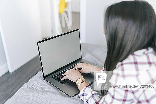Junge Frau  die einen Laptop bei der Arbeit zu Hause benutzt
