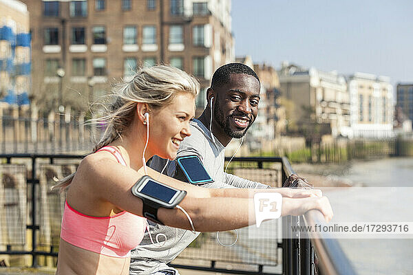 Smiling man and woman leaning on railing while exercising
