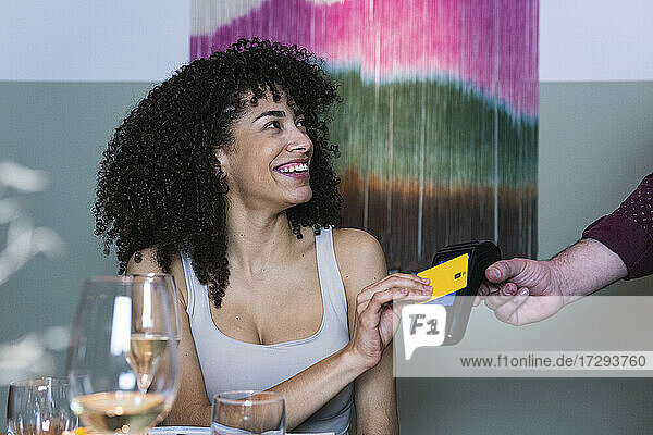 Lächelnde Frau  die in einem Restaurant mit Kreditkarte bezahlt