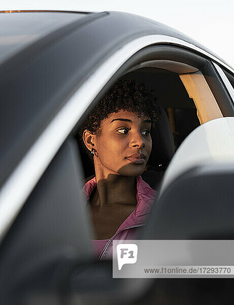 Nachdenkliche Frau  die im Auto vom Fenster wegschaut