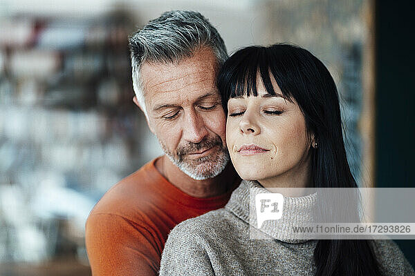 Mature woman leaning with eyes closed on man at cafe