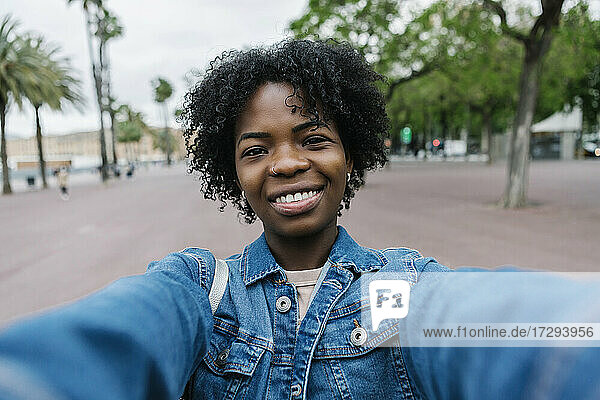 Lächelnde junge Frau mit Afrofrisur macht ein Selfie