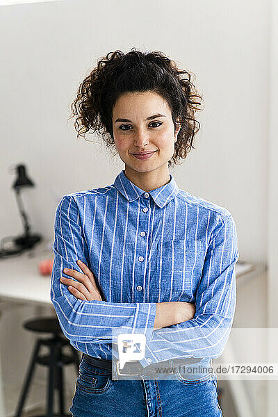 Confident businesswoman with arms crossed standing in office