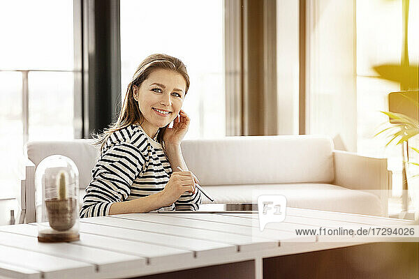 Smiling businesswoman with graphics tablet sitting by sofa at office