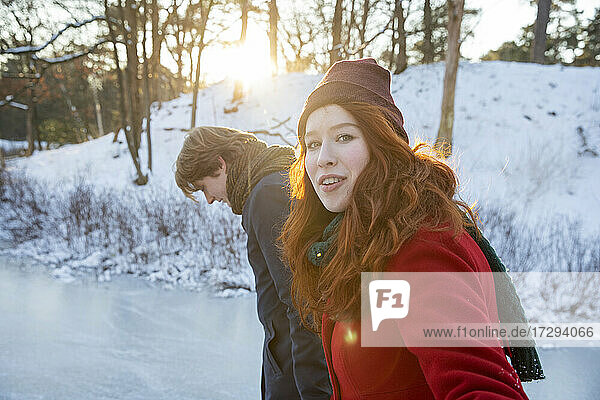 Rothaarige Frau geht mit Freund im Schnee spazieren