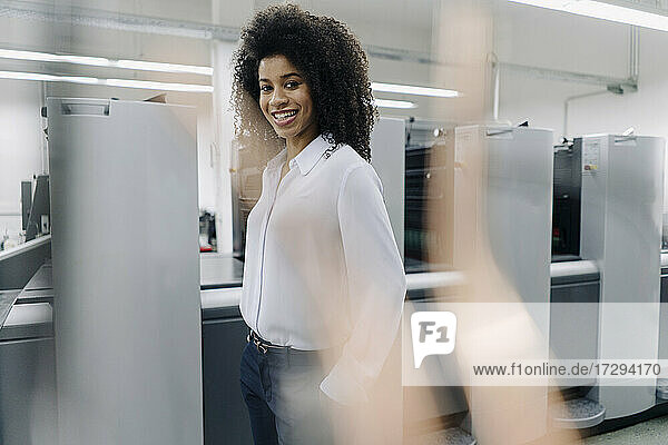 Lächelnde Geschäftsfrau vor Maschinen in der Industrie
