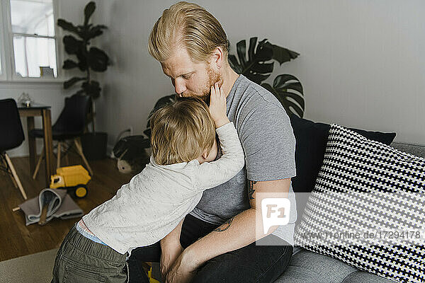 Blond father kissing son's head at home