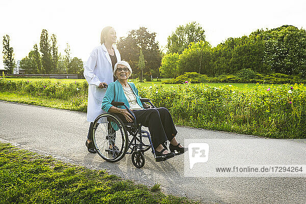 Lächelnde Hausmeisterin mit älterer Frau im Park