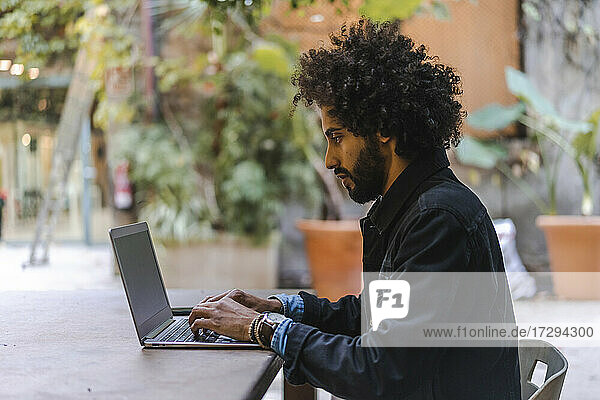 Male entrepreneur using laptop while sitting at sidewalk cafe
